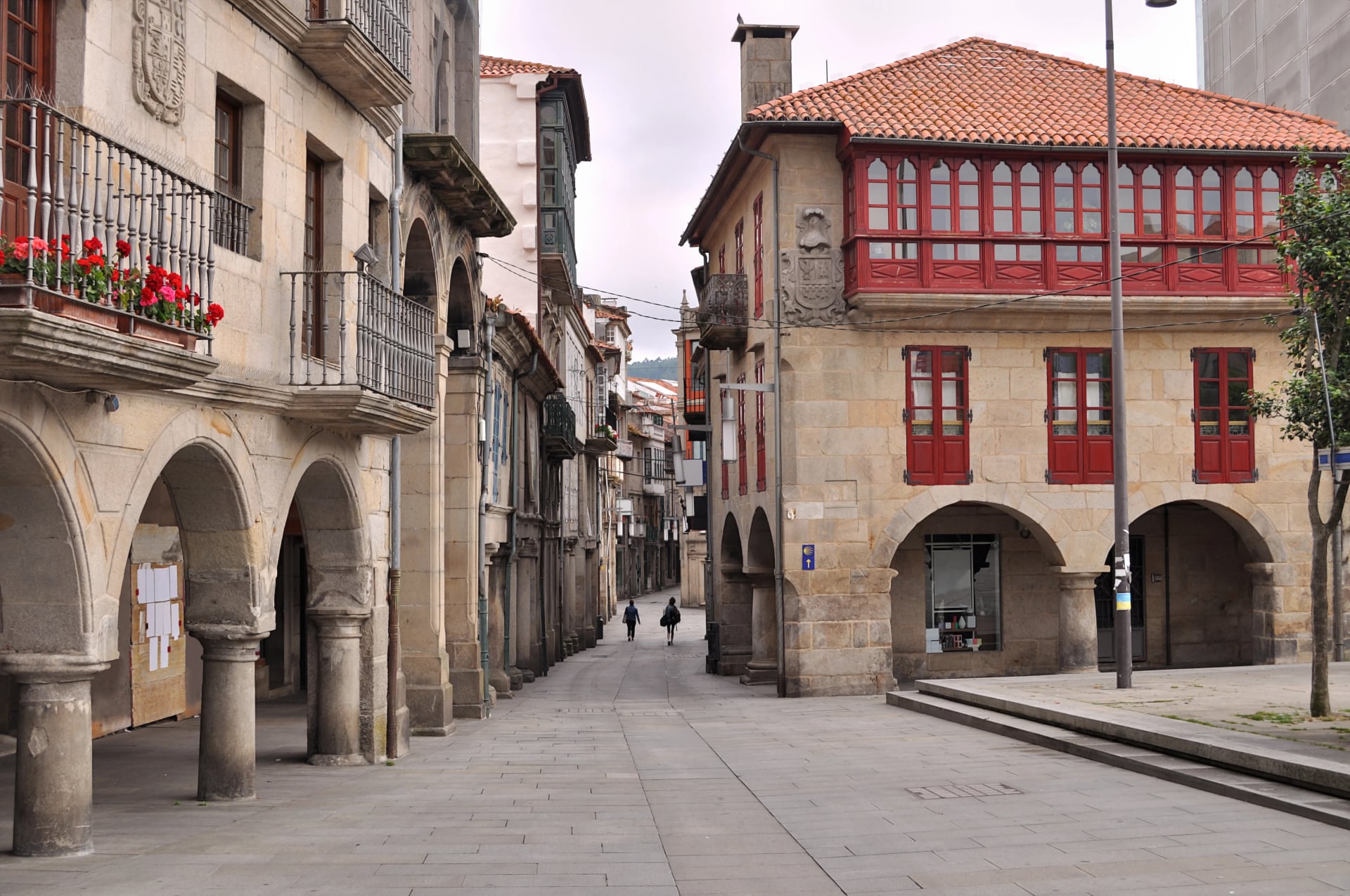 Square of an ancient town in the Galicia region in Spain, Caminhos de Santiago. with two pilgrims walking