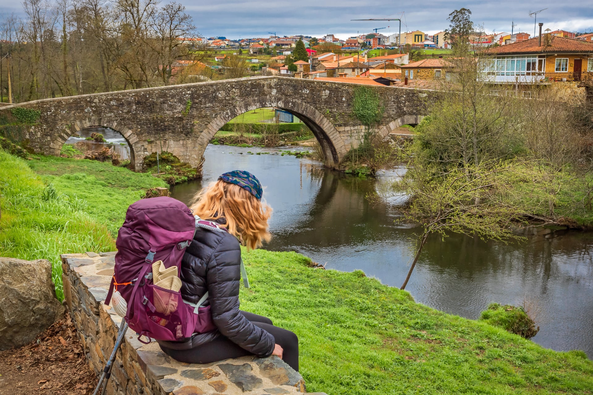 Pilgrim Girl Looking at Medieval Stone Bridge Puente San Xoan in Furelos along the Way of St James Camino de Santiago