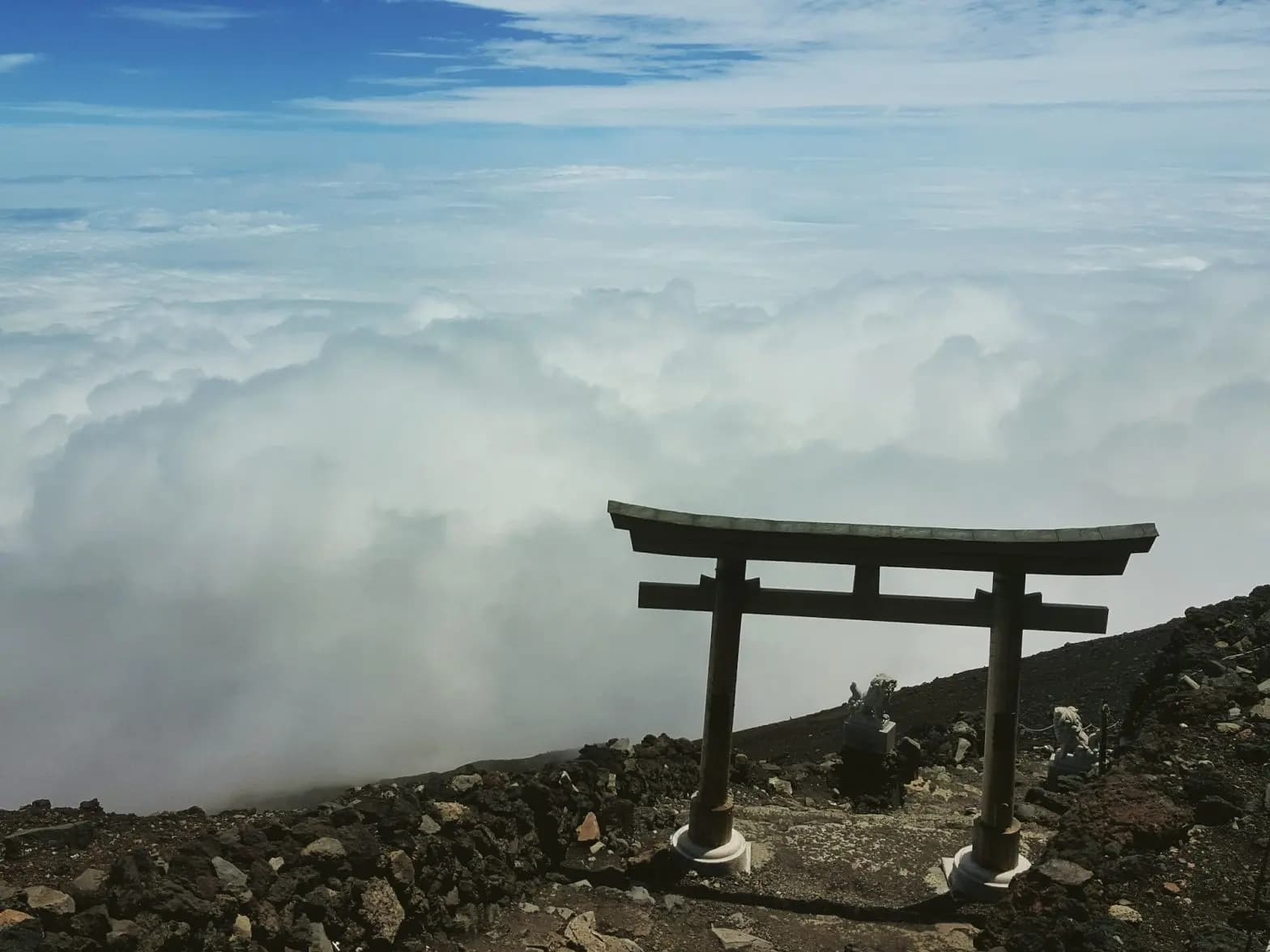 Torii gate on rocky terrain above clouds at Fujinomiya 5th Station.