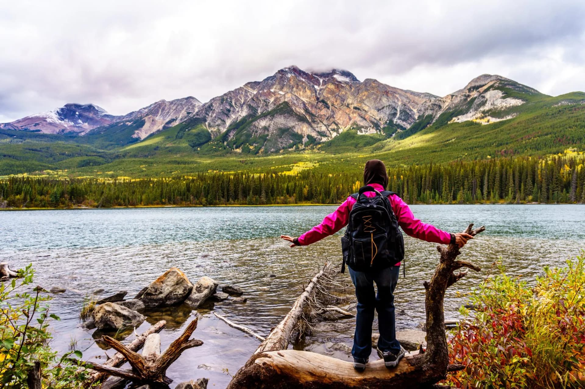 Woman hiker at the edge of Pyramid Lake, near the town of Jasper in Jasper National Park in the Canadian Rockies. Pyramid Mountain in the background