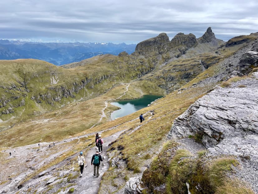 Panoramic view of Schwarzsee, hikers on 5 Lakes Hike at Pizol, St. Gallen, Switzerland.