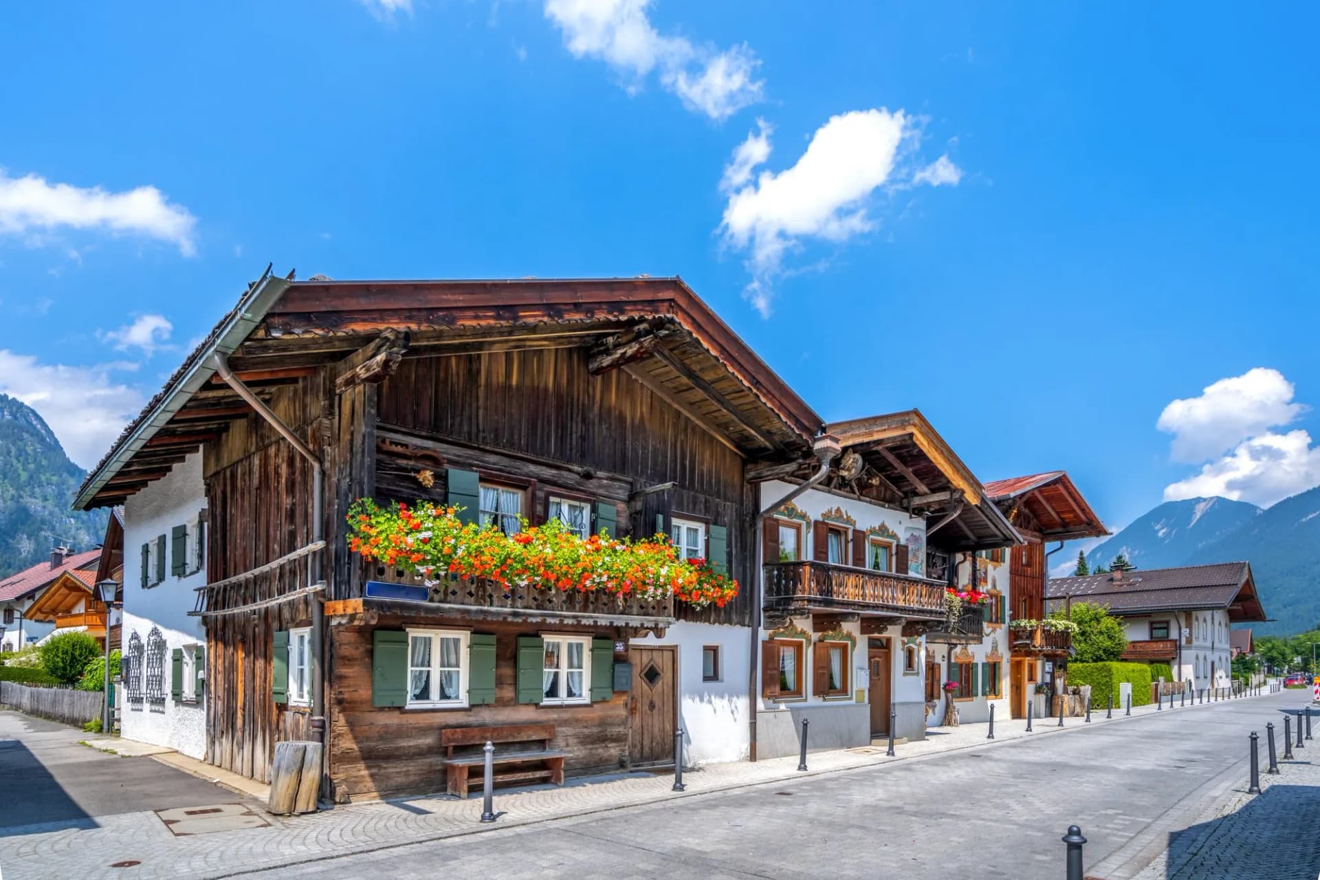 Typical Bavarian architecture in Garmisch-Partenkirchen with wooden facades and flower boxes under blue sky.