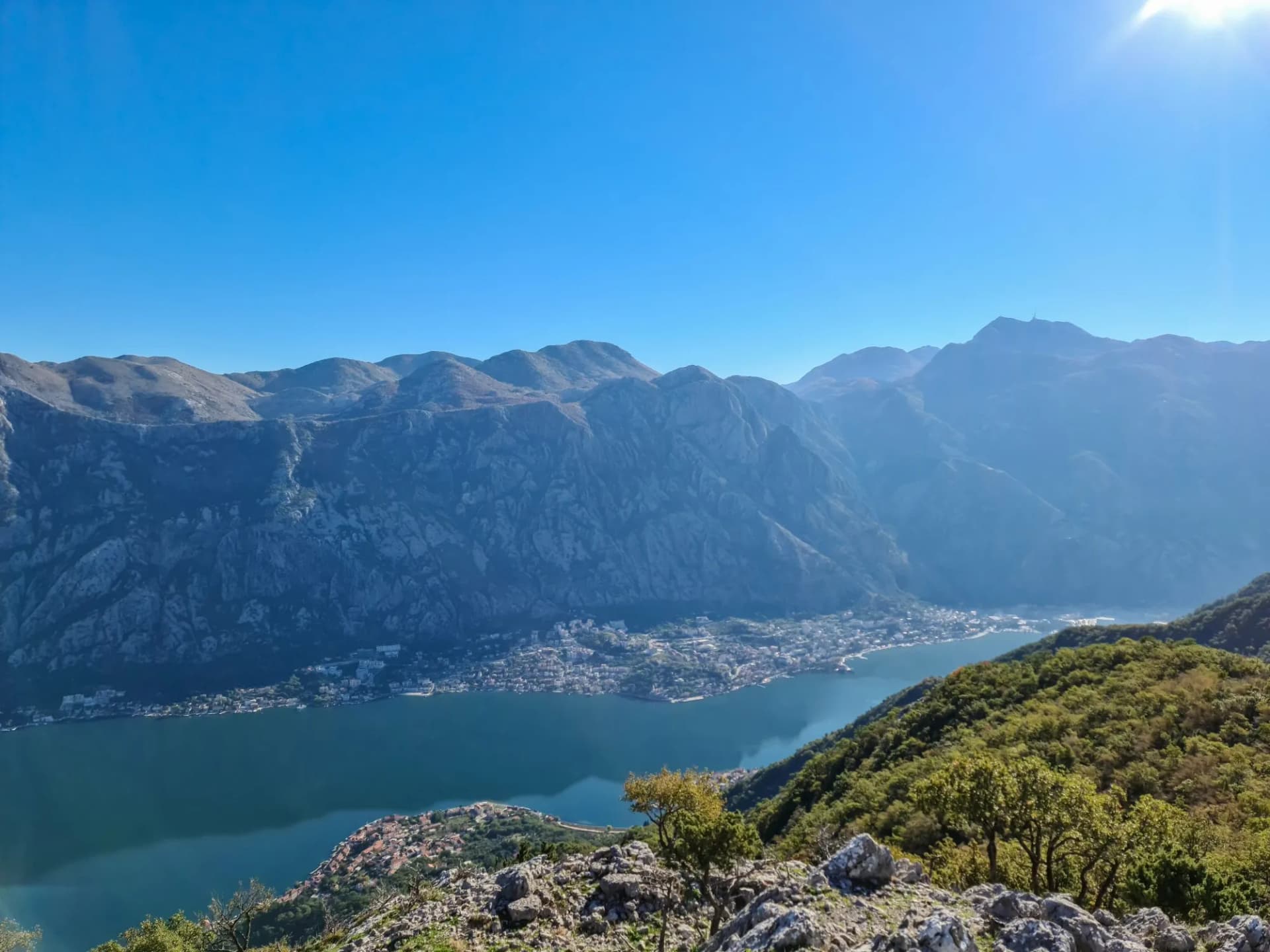Panoramic view from mountain summit of Sveti Ilija on Kotor bay in sunny summer, Adriatic Mediterranean Sea, Montenegro, Balkans, Europe. Fjord winding along steep cliffs. Hiking trail in Dinaric Alps