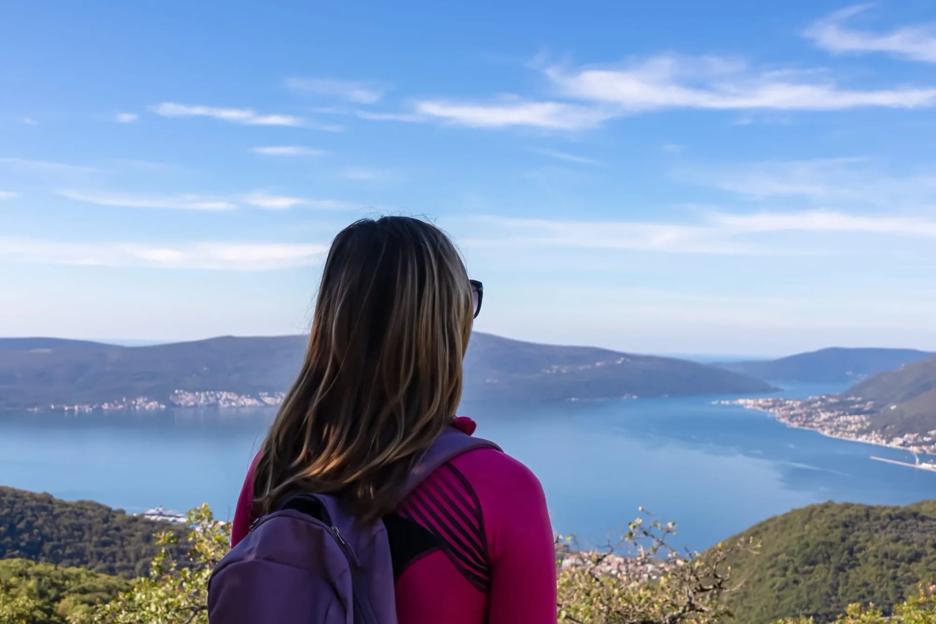 Hiker with backpack viewing Kotor Bay from Vrmac summit, Montenegro, Adriatic Sea.