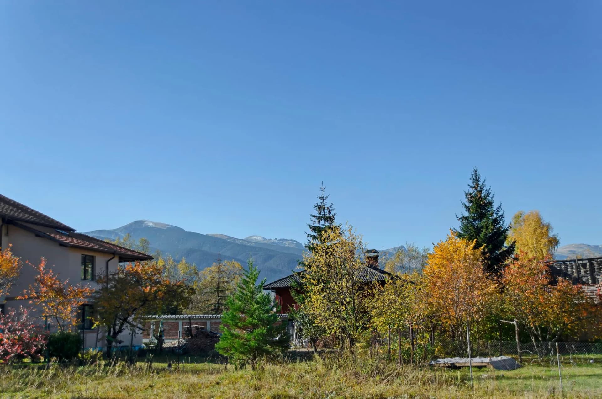 Scene with mountain top, valley, forest, glade and residential district of bulgarian village Govedartsi, Rila mountain, Bulgaria