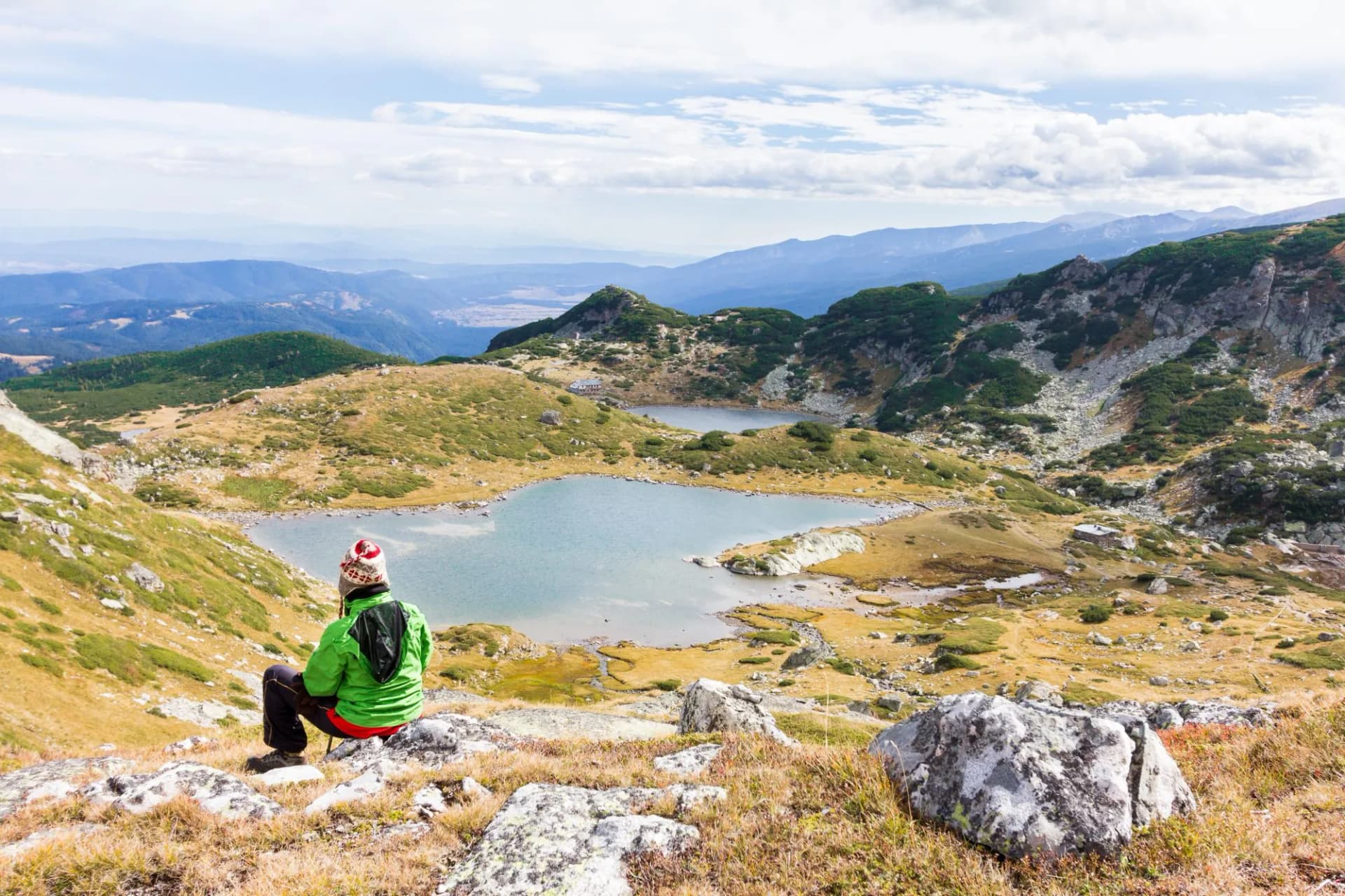 Woman tourist sitting above mountain lake. Seven Lakes, Bulgaria