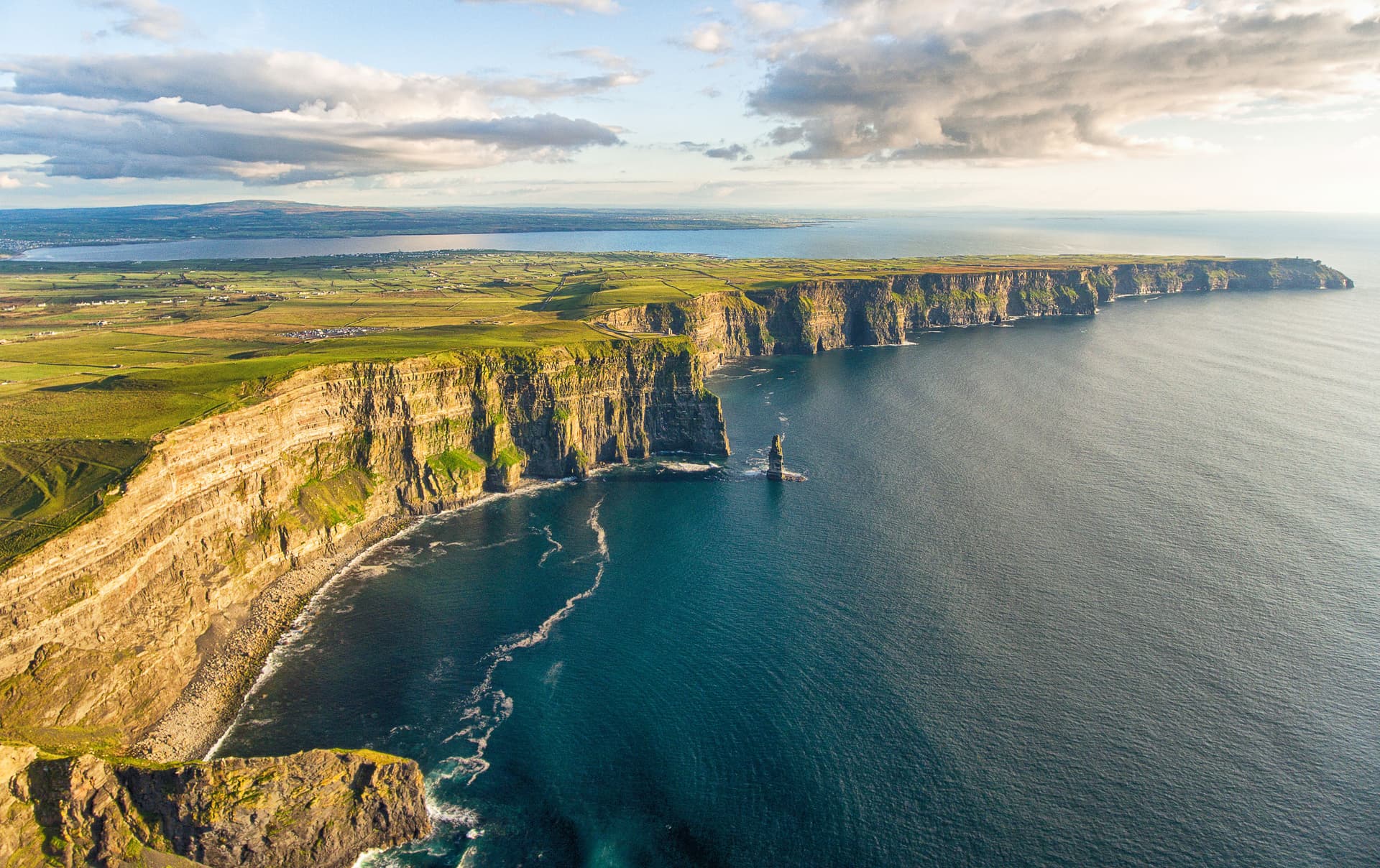 Cliffs of Moher dramatic sea cliffs meeting dark blue ocean water under cloudy sky