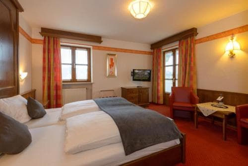 Hotel room with twin beds, dark wood furniture, and red carpet in Bodenmais.