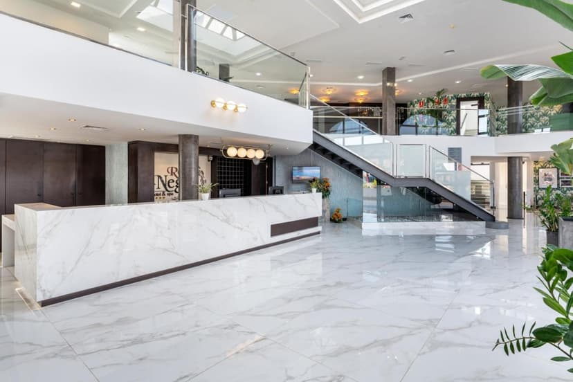 Modern hotel lobby with white marble reception desk, glass railings, and staircase, Occidental Roca Negra.