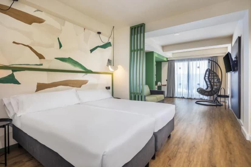 Hotel room with twin beds, abstract mural, and hanging wicker chair near balcony door