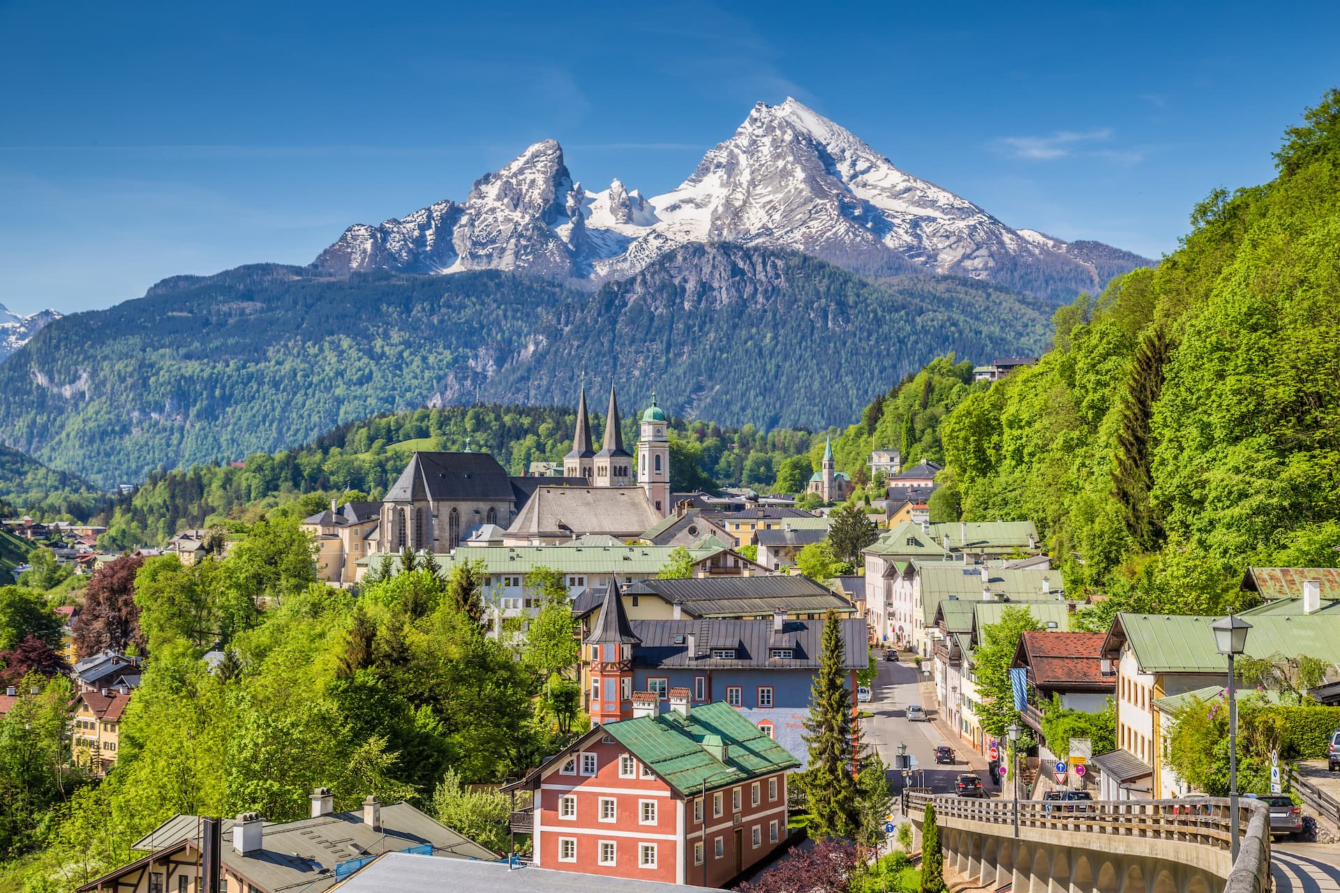 Alpine town of Berchtesgaden with colorful houses below snow-capped Watzmann mountains.