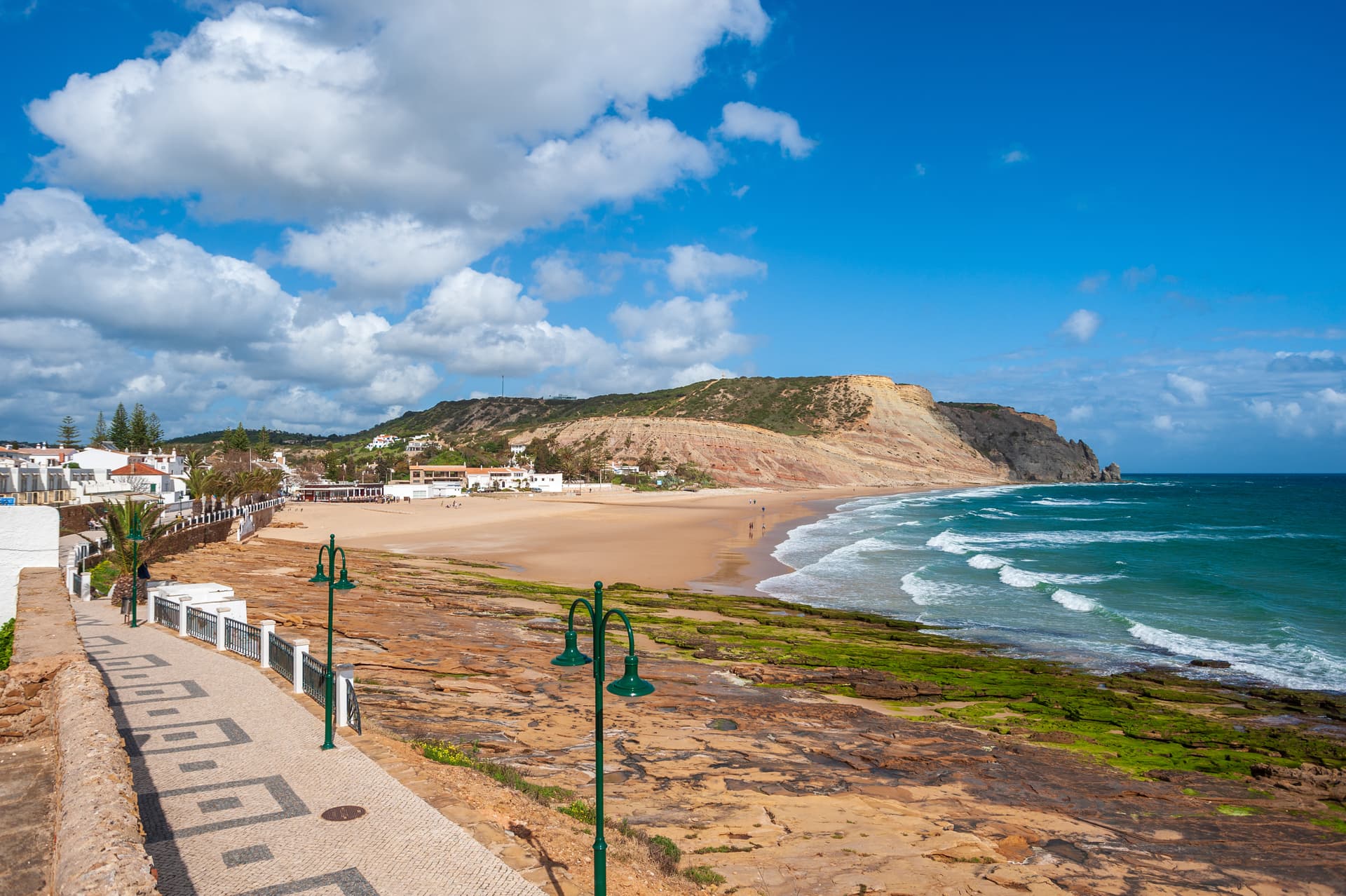 Coastal landscape with Praia da Luz beach, cliffs, and turquoise ocean under blue sky.