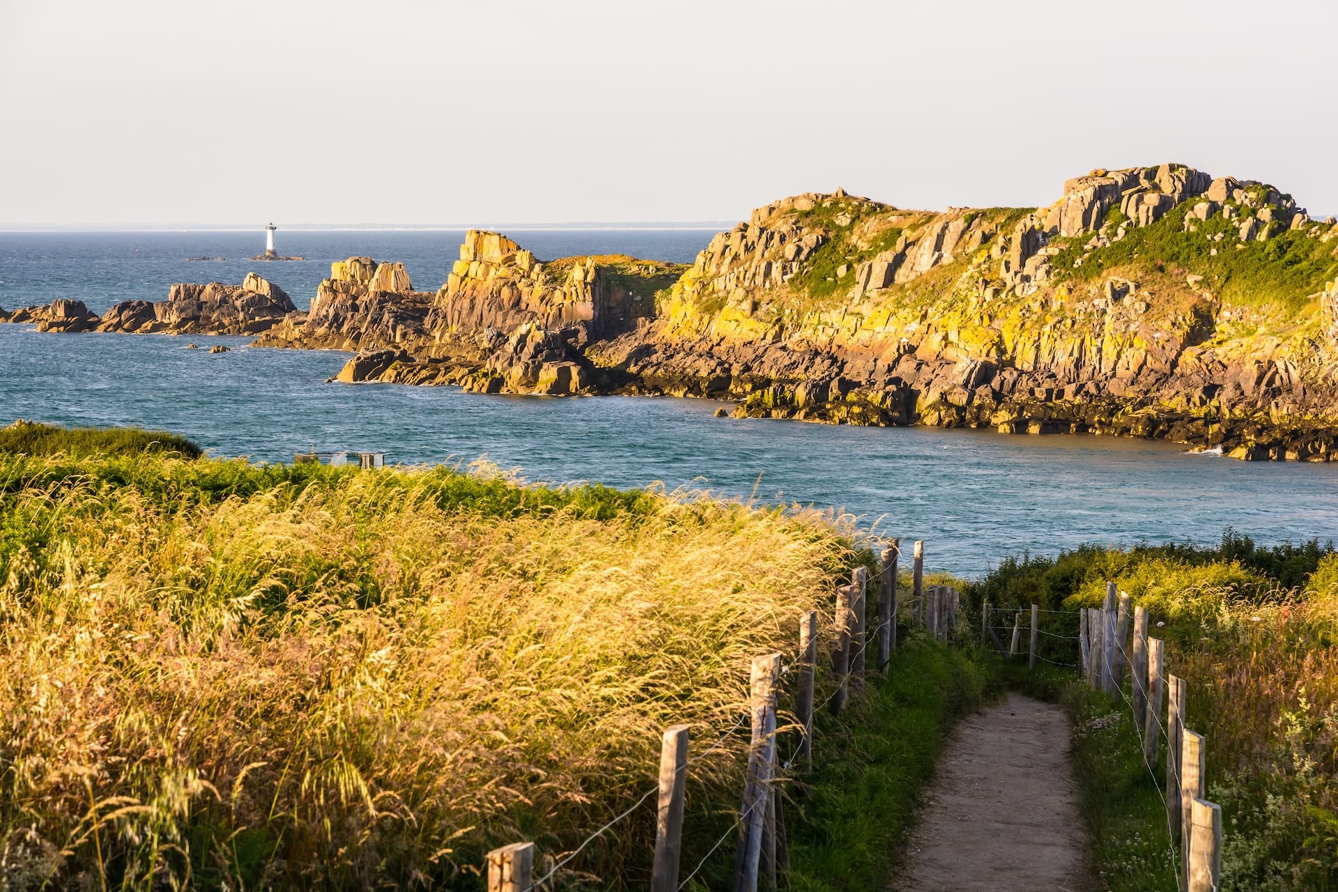 Coastal path overlooking Ile des Landes bird sanctuary, rocks, and lighthouse at Pointe du Groui.