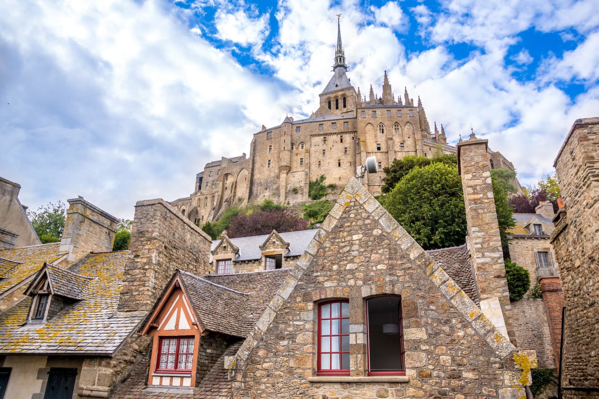 Stone houses in the foreground with Mont Saint-Michel abbey rising on the hill.