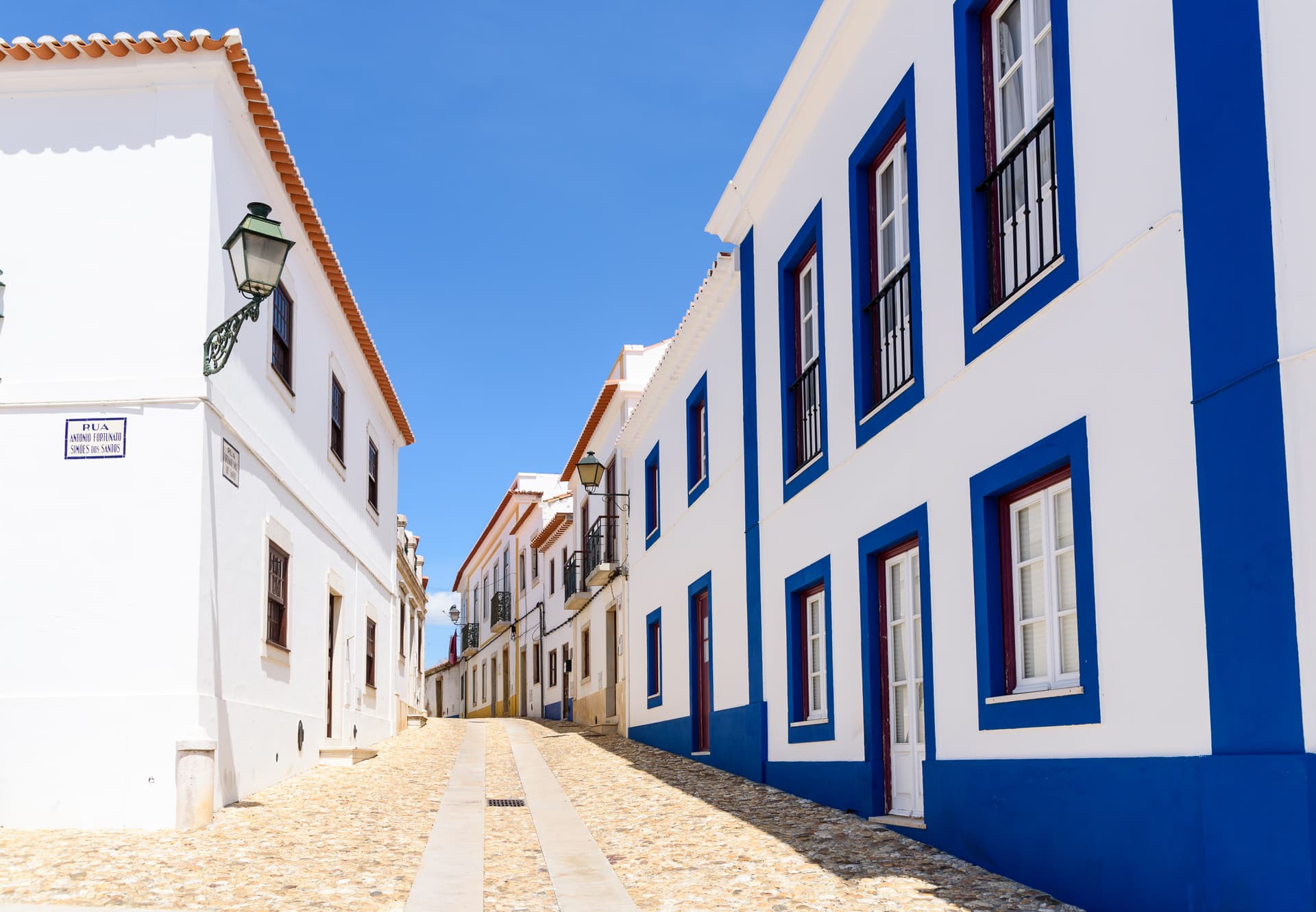Historic street in Odemira, Alentejo, with white buildings trimmed in bright blue under a clear sky.