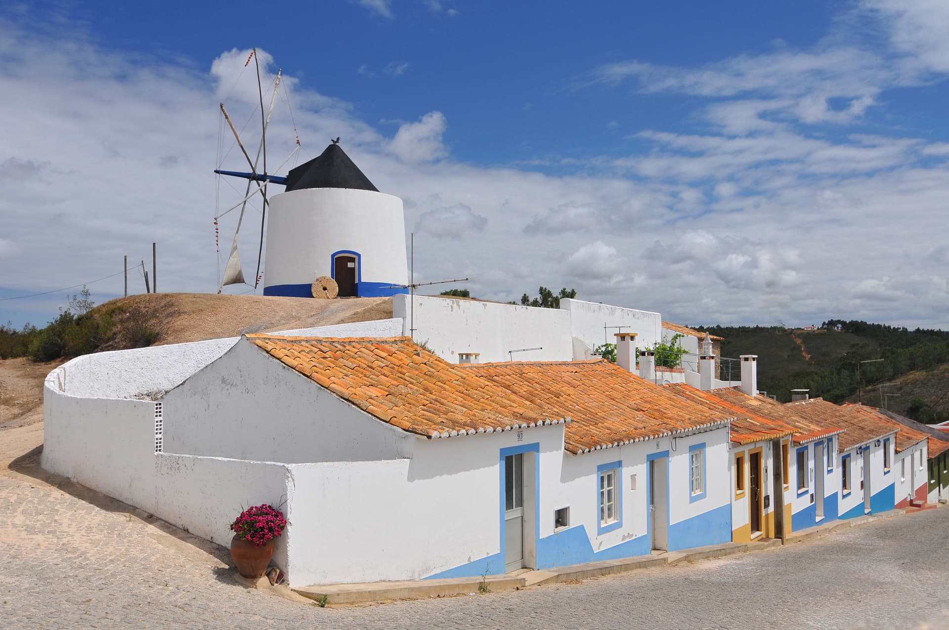 Restored traditional windmill above white houses with orange roofs in Odeceixe, Algarve, Portugal.