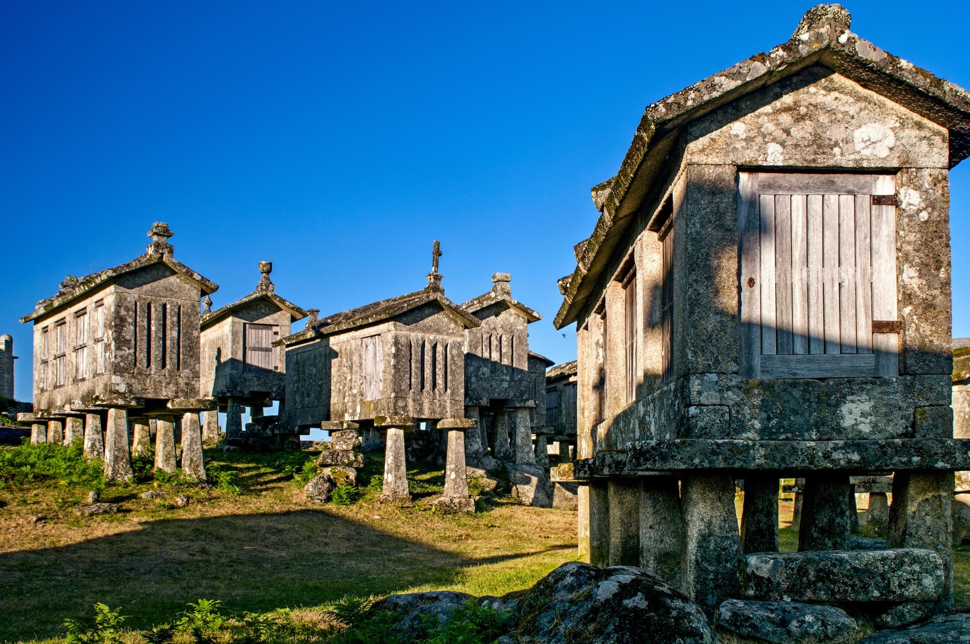 Espigueiros stone granaries on stilts in Lindoso, Portugal, under a clear blue sky.