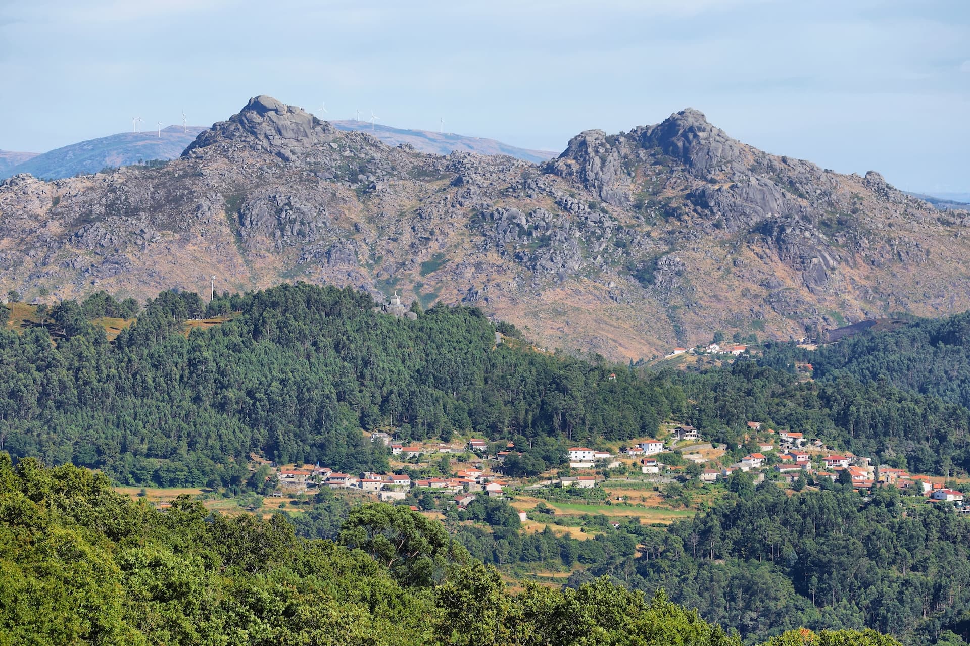 Landscape of Peneda-Gerês National Park with rocky mountains, green forests, and a village.