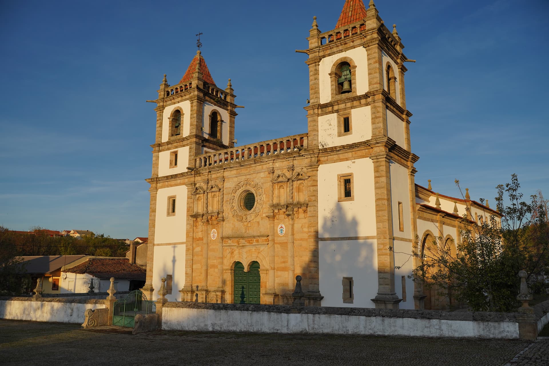 Baroque church with twin bell towers in Outeiro, Portugal, under a clear blue sky.