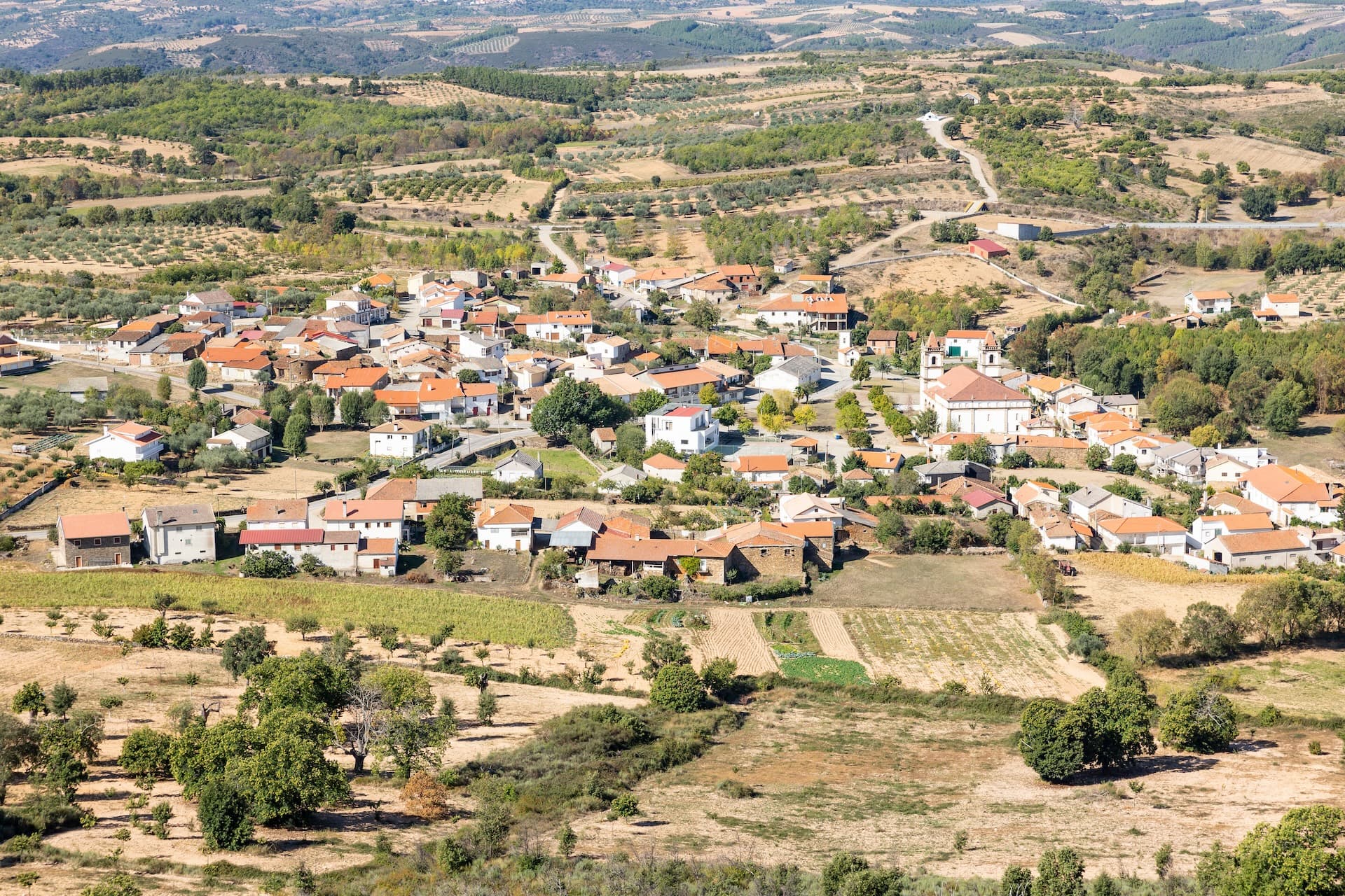 View from castle over Outeiro de Miranda village, Braganca, Portugal, surrounded by dry fields and hills.