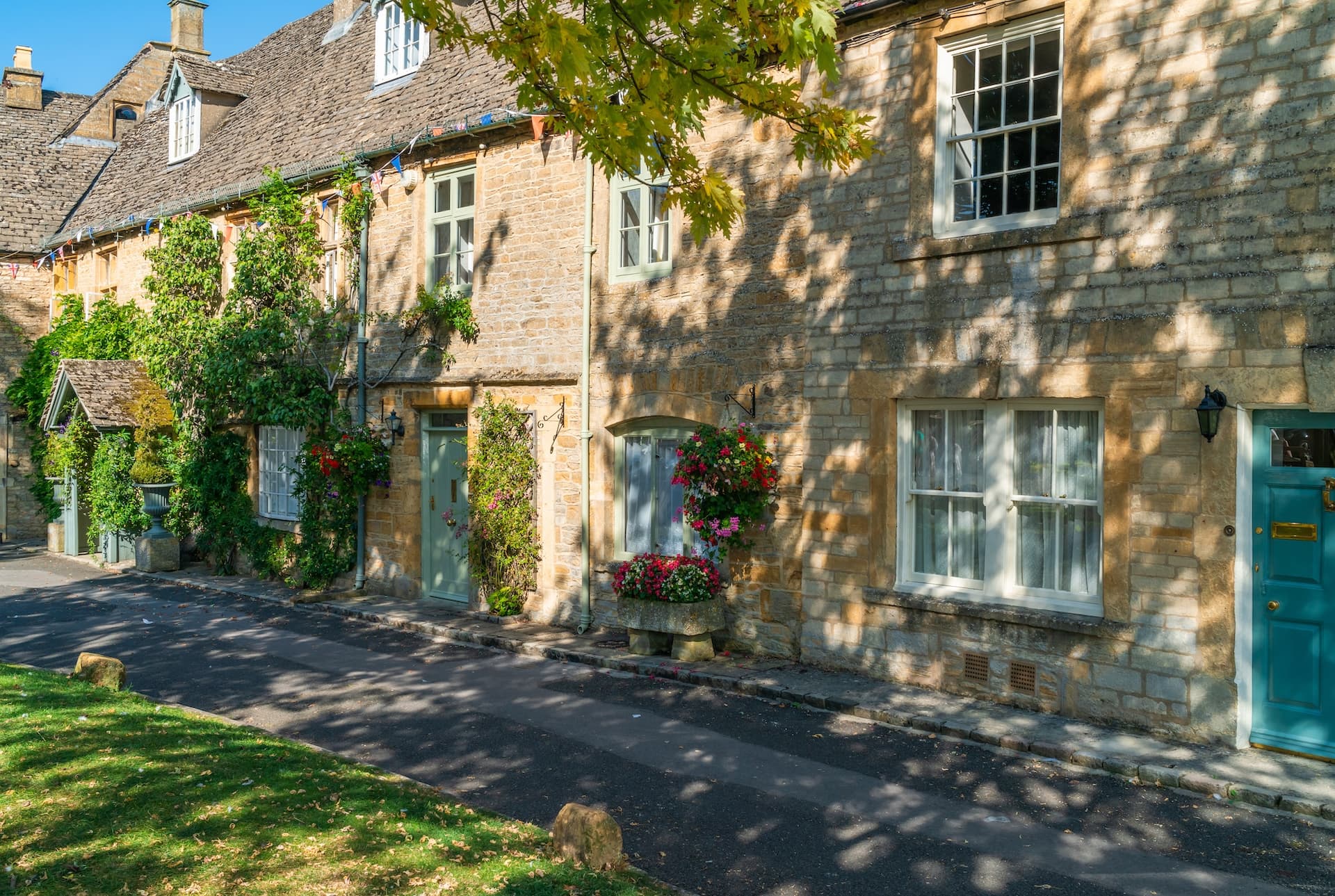 Stone cottages with climbing vines and colorful doors on a street in Stow-on-the-Wold.