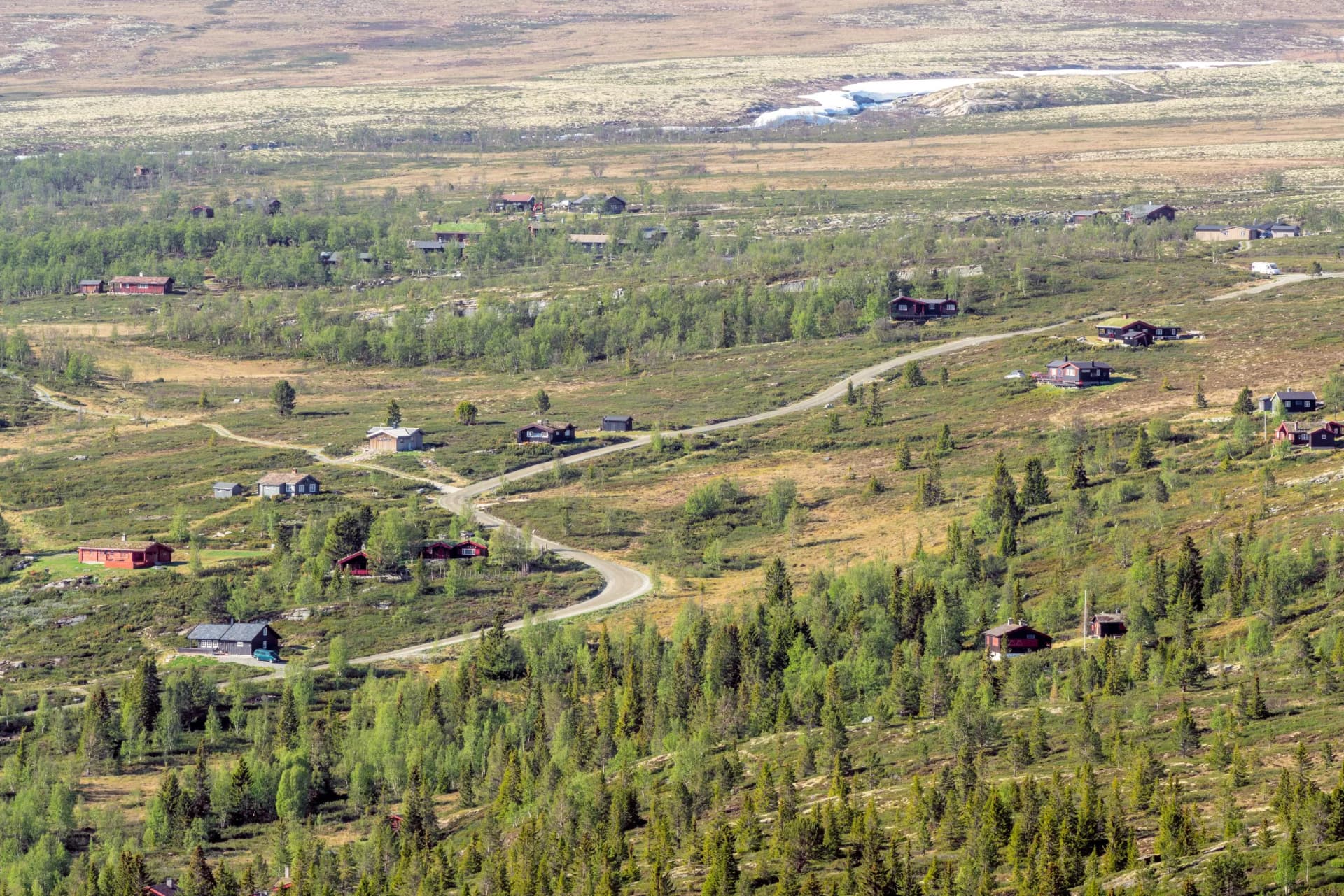 Curved gravel road and family holiday cabins near Rondane national park in Norway.