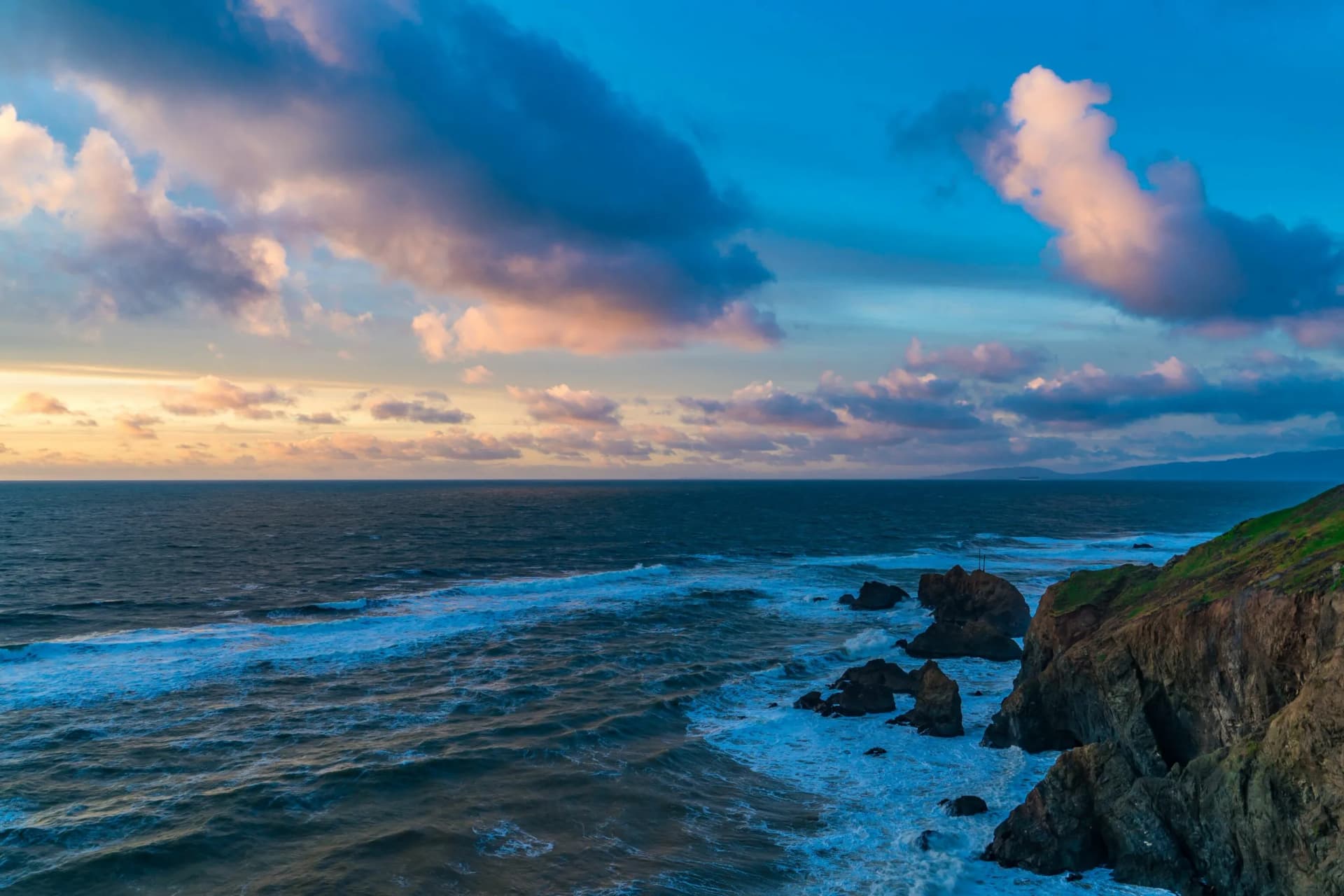 Serene sunset over cliffs and blue waters. Mussel Rock Park, Daly City, California