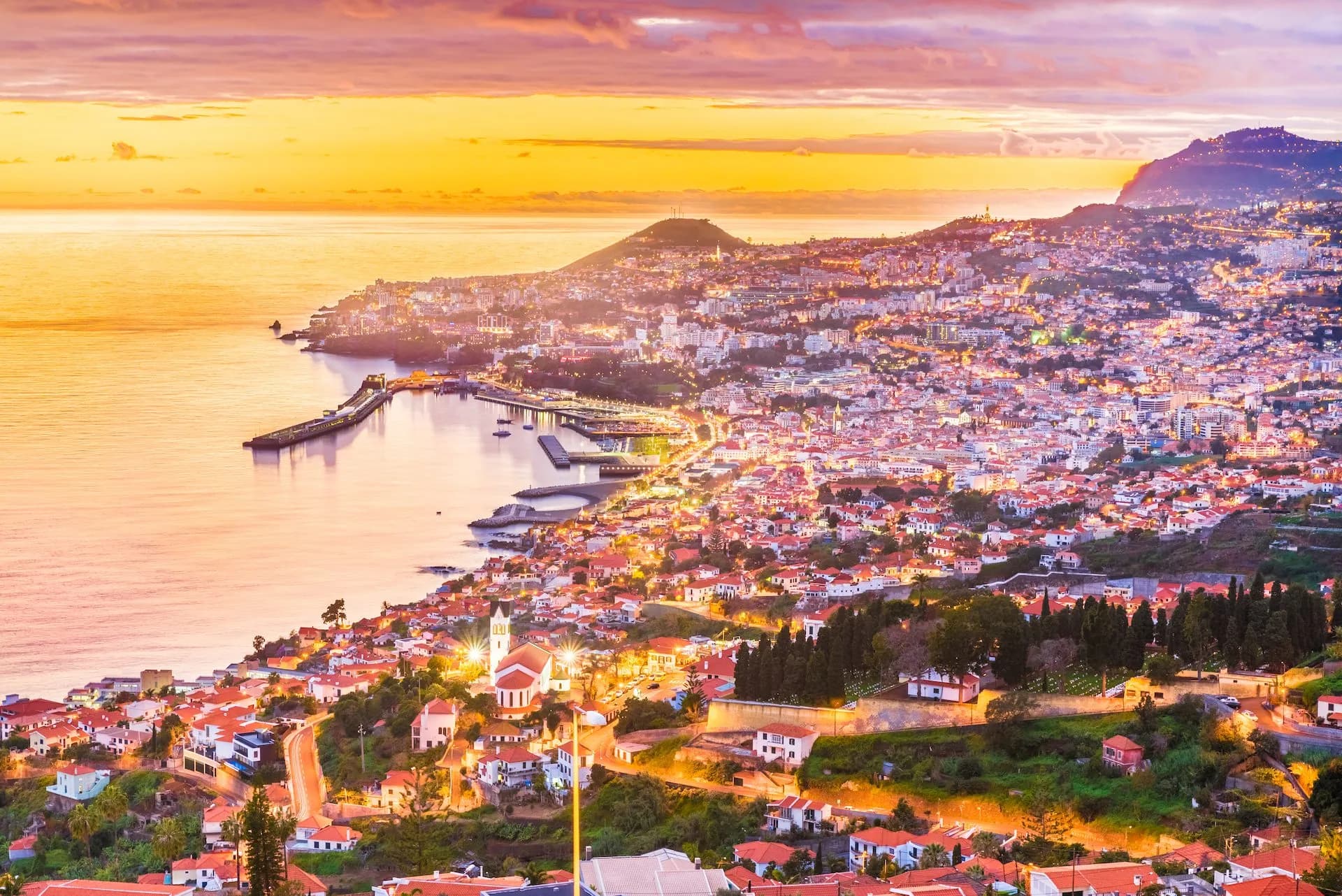 Funchal city lights glowing at sunset overlooking the harbor and Atlantic Ocean, Madeira