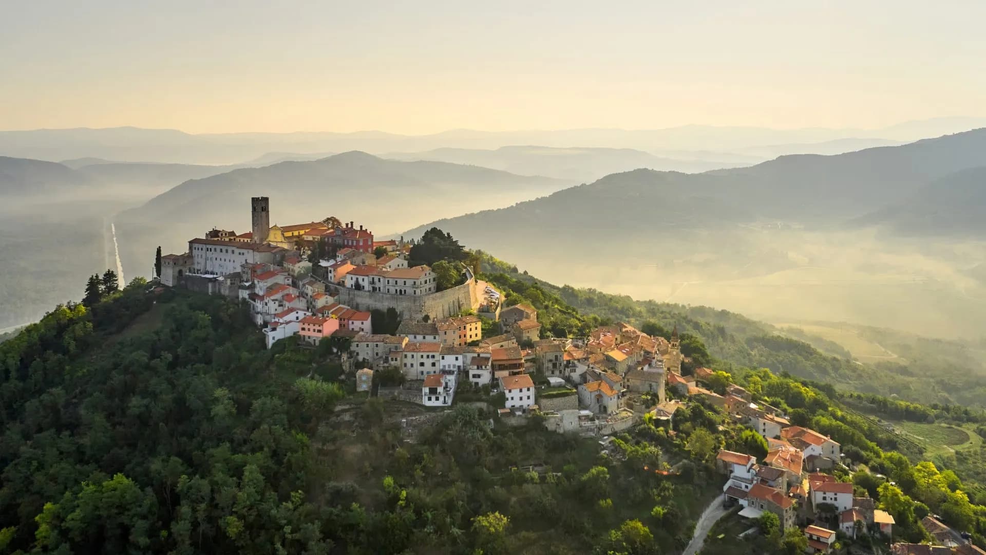 Hilltop town of Motovun in Istria, Croatia, at sunrise over misty valleys.