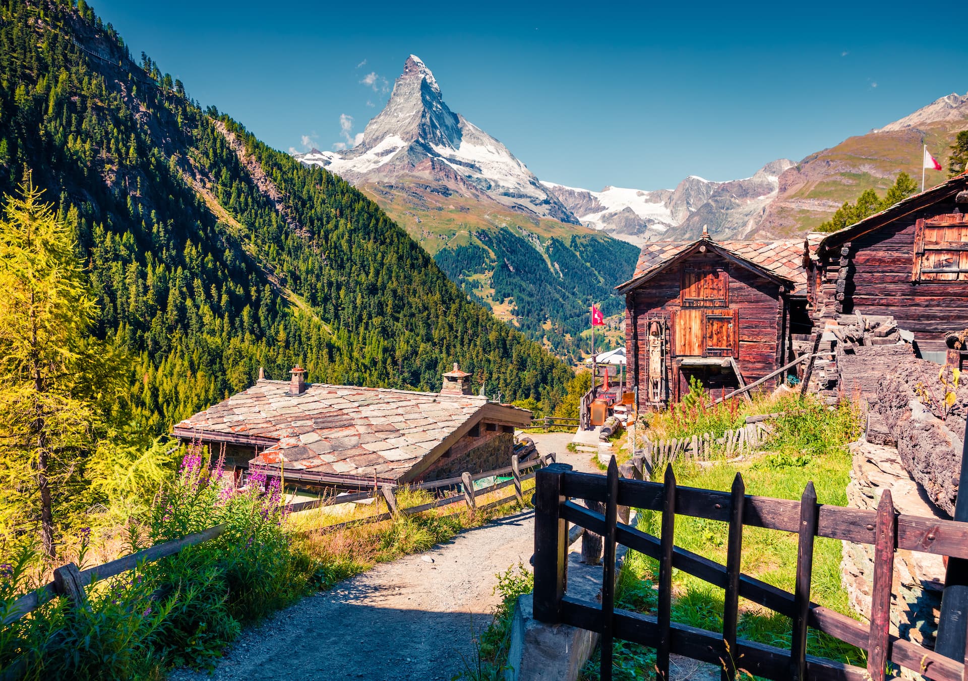 Alpine village path with wooden chalets and Matterhorn mountain peak in Zermatt