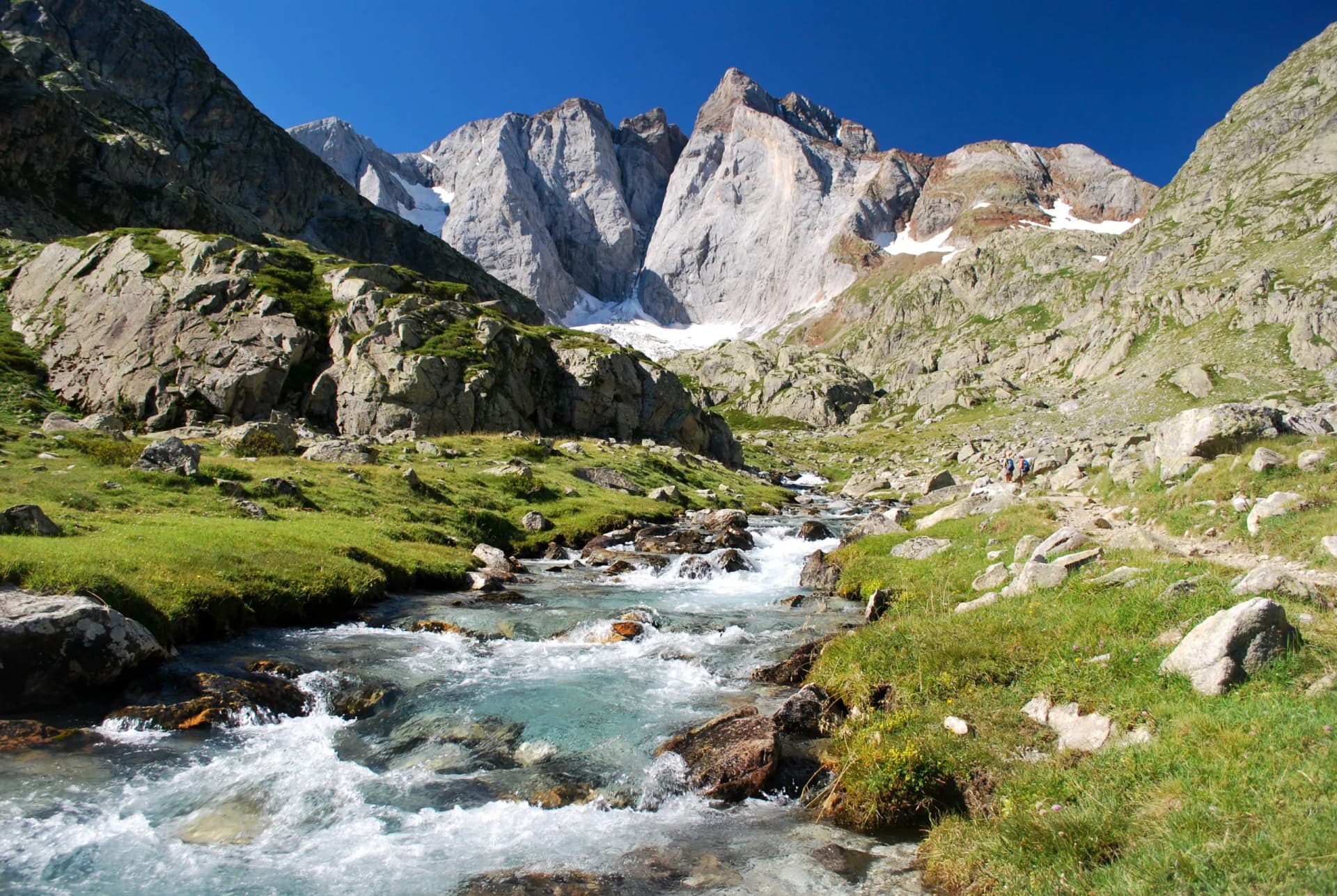 Rushing stream in a rocky alpine valley below massive gray mountains near Cauterets.