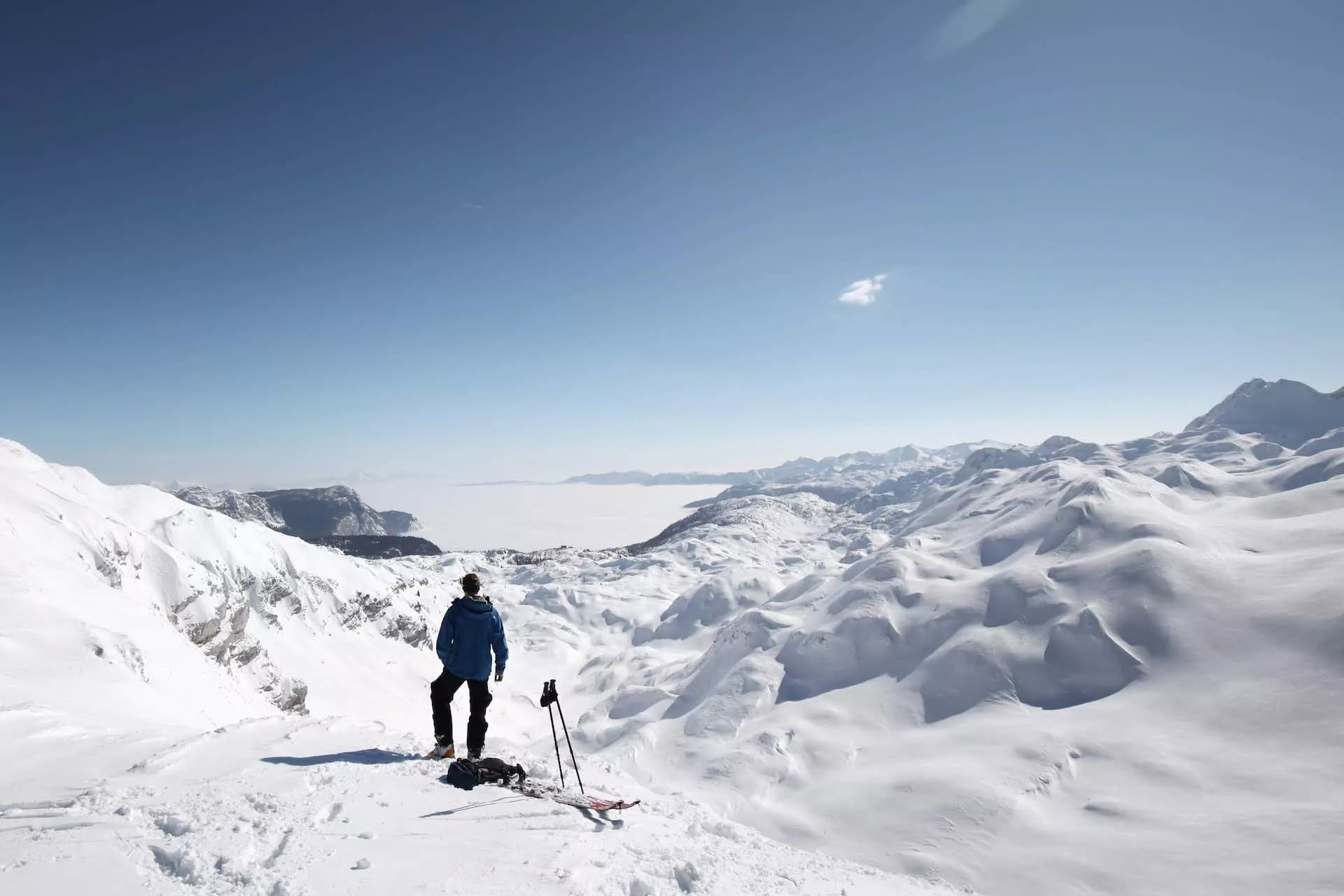 Skier looking over vast snow-covered mountains above a cloud inversion, Komna.