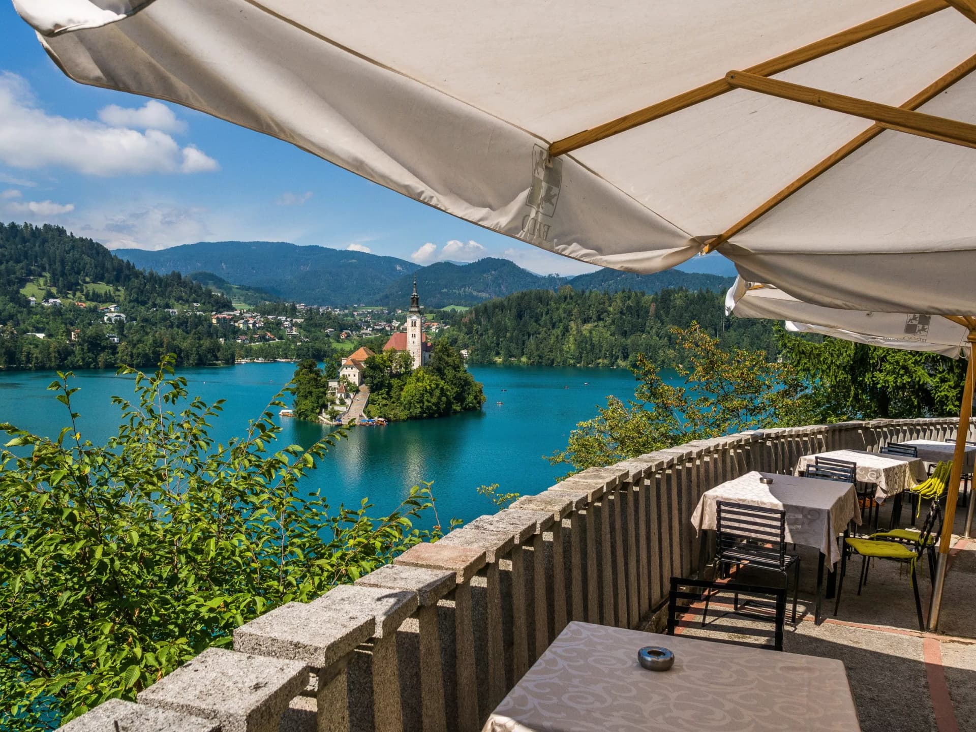 Outdoor cafe terrace overlooking Lake Bled island church and mountains in summer