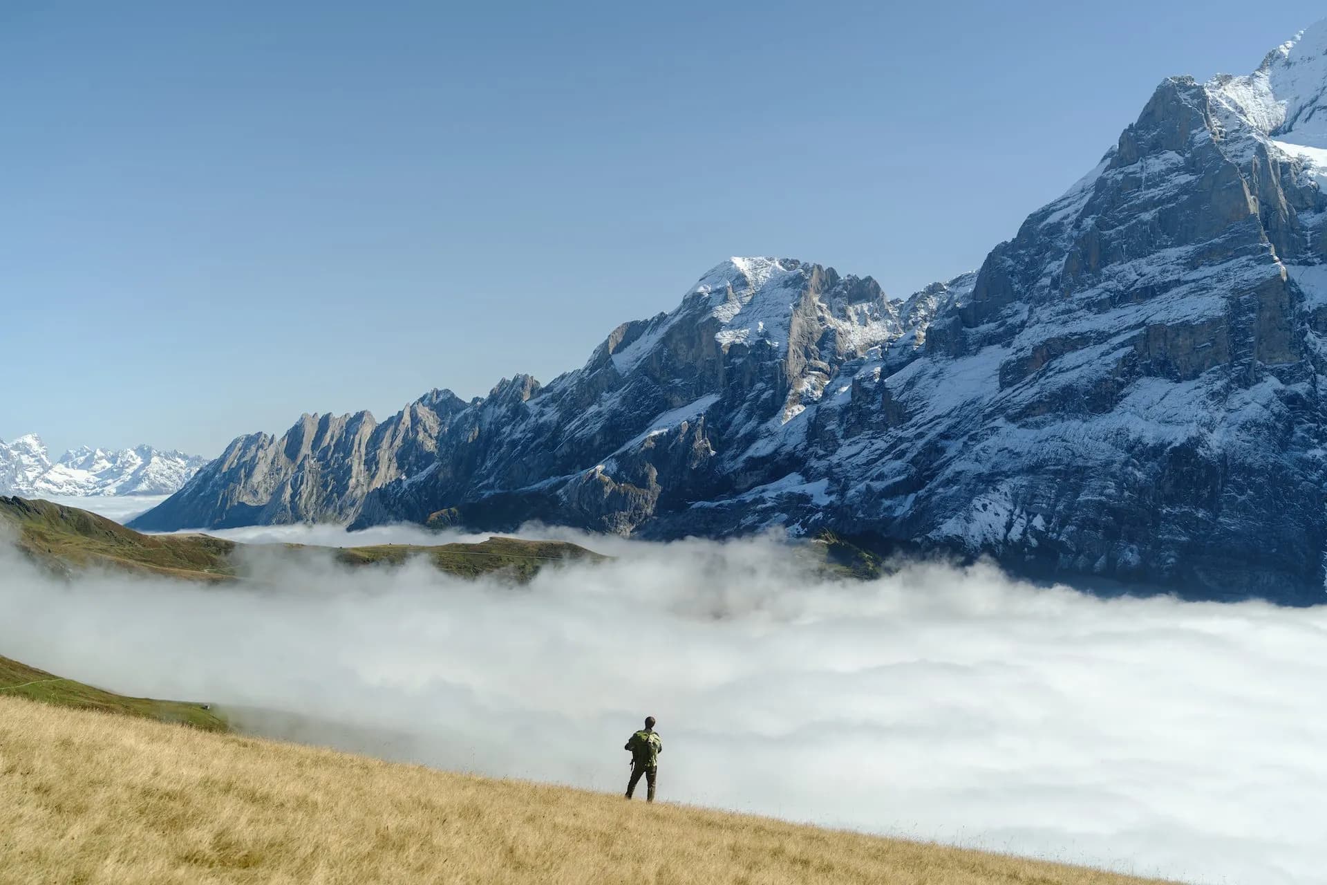Hiker above cloud inversion with snowy Wetterhorn mountains near Grindelwald.